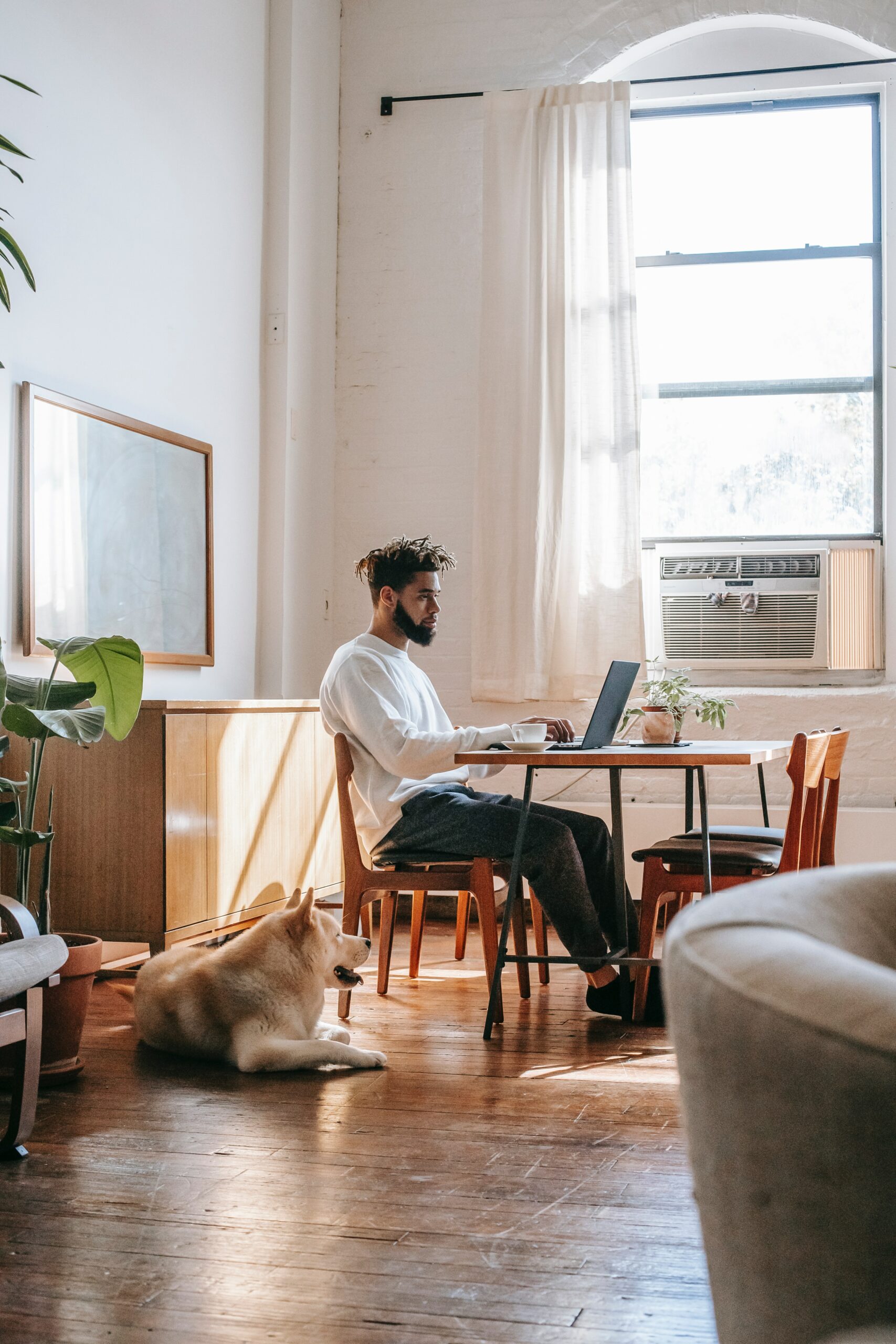 Mann arbeitet im Wohnzimmer, Hund liegt daneben